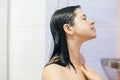 Young happy woman taking shower at home or hotel bathroom. Beautiful  brunette girl washing her hair and enjoying relax time. Body Royalty Free Stock Photo