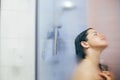 Young happy woman taking shower at home or hotel bathroom. Beautiful  brunette girl washing her hair and enjoying relax time. Body Royalty Free Stock Photo