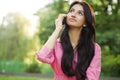 Young happy woman talking on cell phone sitting on grass in summer city park Royalty Free Stock Photo