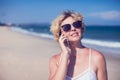 Young happy woman talking on mobile phone on a beach with sea ba Royalty Free Stock Photo