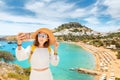 Happy woman tourist taking selfie photo on her smartphone with view on a sandy beach and old town. Vacaction and travel Royalty Free Stock Photo