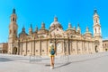 Happy woman tourist walking near the famous cathedral Del Pilar on the central square during summer vacation in Zaragoza Royalty Free Stock Photo