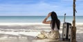 Young happy woman with travel suitcase sits on the beach in summer. Travel woman looks at the sea. Women sitting and relax with Royalty Free Stock Photo