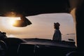 Young happy woman traveler enjoying sunset on sea beach, shot through car window Royalty Free Stock Photo