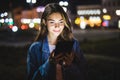 Young happy woman using tablet outdoors over blurry night city lights Royalty Free Stock Photo