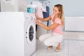 Woman Using Washing Machine In Utility Room Royalty Free Stock Photo