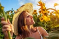 Young happy woman walking in blooming sunflower field feeling free smelling flowers. Summer vacation Royalty Free Stock Photo