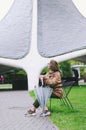 Young happy woman walking in the rain in green park with umbrella, smiling, fun. person sitting on the bench. Cold weather Royalty Free Stock Photo