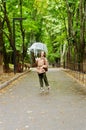 Young happy woman walking in the rain in green park with umbrella, smiling, fun. person sitting on the bench. Cold weather Royalty Free Stock Photo