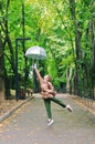 Young happy woman walking in the rain in green park with umbrella, smiling, fun. person sitting on the bench. Cold weather Royalty Free Stock Photo