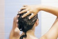 Young happy woman washing her hair with shampoo, hands with foam closeup. Back of beautiful brunette girl taking shower and Royalty Free Stock Photo