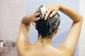 Young happy woman washing her hair with shampoo, hands with foam closeup. Back of beautiful brunette girl taking shower and Royalty Free Stock Photo