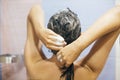 Young happy woman washing her hair with shampoo, hands with foam closeup. Back of beautiful brunette girl taking shower and Royalty Free Stock Photo