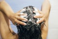 Young happy woman washing her hair with shampoo, hands with foam closeup. Back of beautiful brunette girl taking shower and Royalty Free Stock Photo