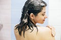 Young happy woman washing her hair with shampoo, wet hair with foam. Back of beautiful brunette girl taking shower and enjoying Royalty Free Stock Photo