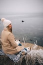 Young happy woman holding cup of tea enjoying winter frozen nature by the sea Royalty Free Stock Photo