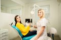 Young happy woman client looking at the mirror with toothy smile at the dental office near the doctor Royalty Free Stock Photo