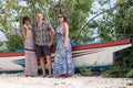 Young happy women and man posing near old ship at tropical white sand beach. Bali, Indonesia. Royalty Free Stock Photo