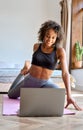 Young healthy Afro American girl watching online fitness class sitting on mat. Royalty Free Stock Photo