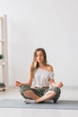 Young healthy beautiful woman practicing yoga at home sitting in lotus pose on yoga mat meditating smiling relaxed with Royalty Free Stock Photo