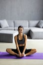 Young healthy beautiful woman in sportive top and leggings practicing yoga at home sitting in lotus pose on yoga mat meditating Royalty Free Stock Photo