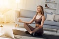 Young healthy beautiful woman in sportive top and leggings practicing yoga at home sitting in lotus pose on yoga mat Royalty Free Stock Photo