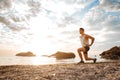 Young healthy man athlete doing squats at the beach