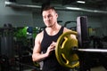 Young healthy man with big muscles holding disk weights in gym. Fitness, sport, training, motivation and lifestyle Royalty Free Stock Photo