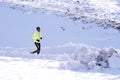 Young healthy sport man running in snow mountains in trail runner hard workout in winter