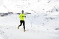 Young healthy sport man running in snow mountains in trail runner hard workout in winter Royalty Free Stock Photo