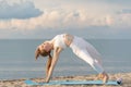 Young healthy woman practicing yoga on sea background. Slim girl doing yoga on the beach Royalty Free Stock Photo
