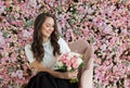 Young healthy woman smiling and holding colorful pink color flower bouquet on floral spring or summer background, studio fashion Royalty Free Stock Photo