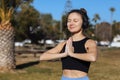 Young healthy woman in sportswear listens music in headphones while doing fitness squat leg exercises outdoors in park Royalty Free Stock Photo