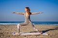 Young healthy woman in a stylish one-piece jumpsuit practicing yoga on the beach at sunrise Royalty Free Stock Photo