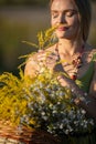 A young woman savors the scent of flowering herbs. Common goldenrod and wintercress.