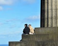 Young heterosexual caucasian couple sitting on steps enjoying view over Edinburgh at Calton Hill