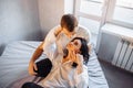 Young heterosexual couple of young lovers indulge in bed at home. Girl lies on legs of boyfriend and hugging his face with hand. Royalty Free Stock Photo