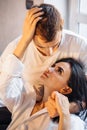 Young heterosexual couple of young lovers indulge in bed at home. Girl lies on legs of boyfriend and hugging his face with hand. Royalty Free Stock Photo