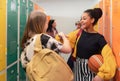 Young high school students meeting and greeting near locker in campus hallway talking and high fiving. Royalty Free Stock Photo
