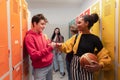 Young high school students meeting and greeting near locker in campus hallway talking and high fiving. Royalty Free Stock Photo