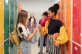 Young high school students meeting and greeting near locker in campus hallway talking and high fiving. Royalty Free Stock Photo