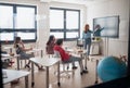 Young High school teacher giving marketing lesson to students in classroom Royalty Free Stock Photo