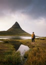 Young hiker with a backpack looks at the Kirkjufell mountain in Iceland Royalty Free Stock Photo