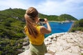 Young hiker explorer girl taking picture with smartphone of natural tropical panoramic view. Wide angle. Windy day