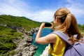 Young hiker girl taking photo with smartphone of natural tropical landscape. Wide angle