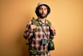 Young hiker man with curly hair and beard hiking wearing backpack and water canteen making fish face with lips, crazy and comical