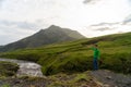 Young hiker man with river and green mountains on background on the Fimmvorduhals hiking trail in Iceland. Concept of