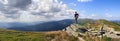 Young hiker man standing on top of cliff taking a selfie on background mountain range of Chernogor in Ukraine. Carpathian summer Royalty Free Stock Photo
