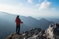 Young hiker Man standing with trekking poles on cliff edge and looking at Tatra mountains valley. Successful summit concept image.