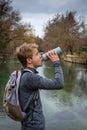 Young hiker with rucksack drinking from waterbottle beside river Royalty Free Stock Photo